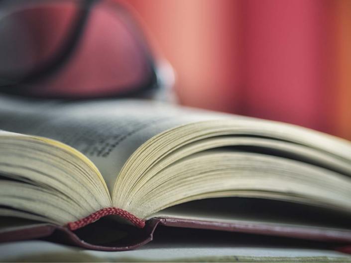 large book with a pair of glasses sitting on top.