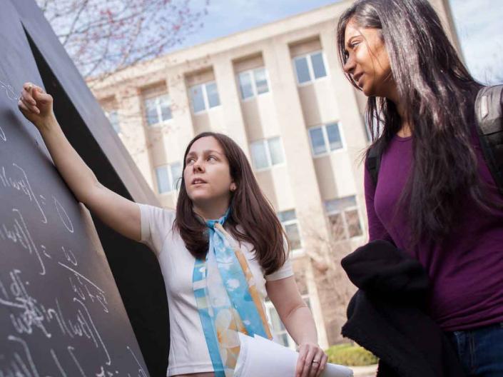 Students drawing on chalkboard outside