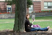 girl reading against tree outside