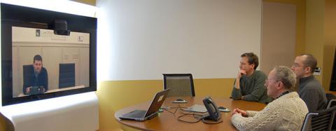 people at a confernence table talking to someone else via videoconference