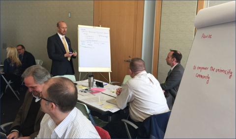 Speaker at a whiteboard while others are listening and seated