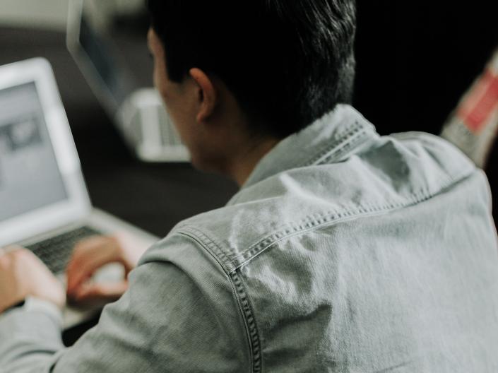 Man sitting, typing on a computer
