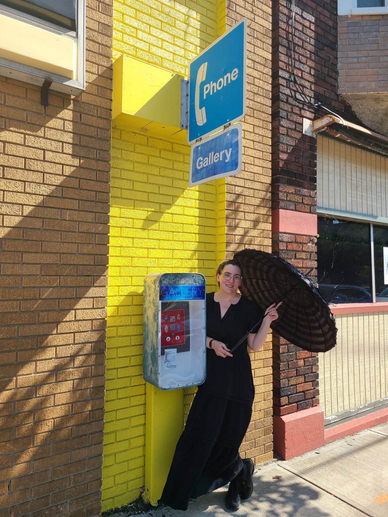Woman with umbrella standing in front of a phone booth