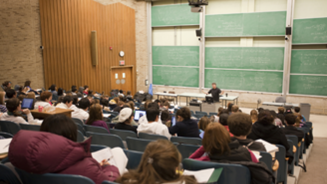 Full lecture hall with students listening to Professor