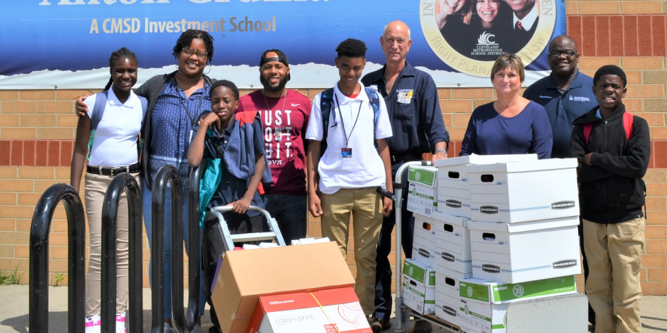 Several people standing in front of a wall with carts full of school supplies