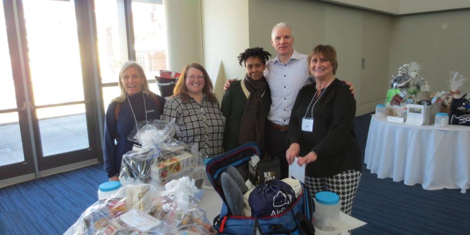 Five people standing in front of a table with gifts on it