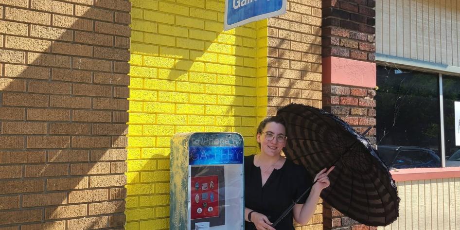 Woman with umbrella standing in front of a phone booth