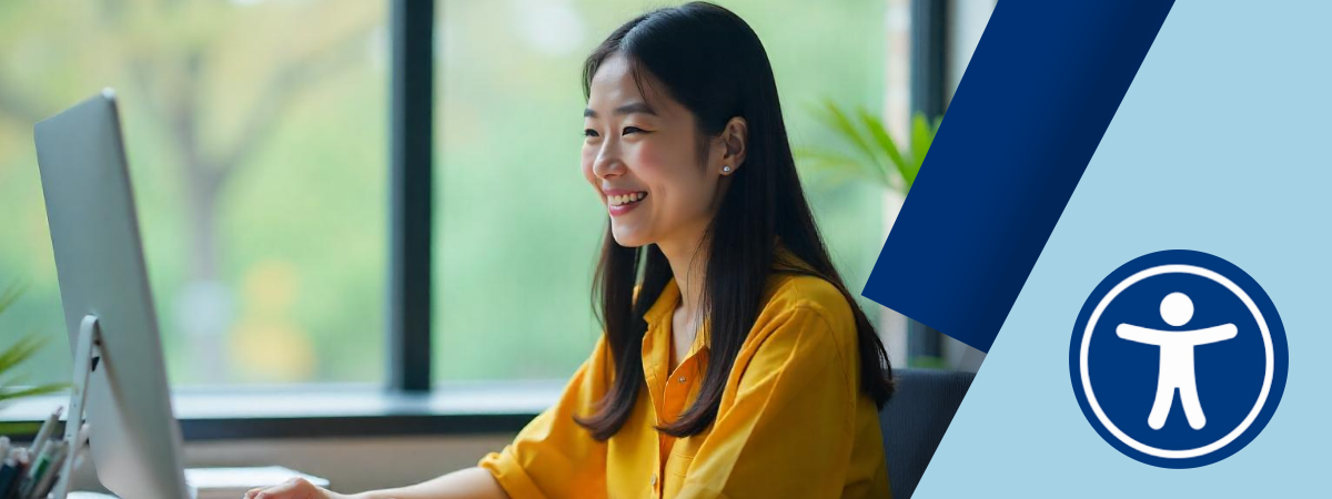 A woman sits at her desk, smiling at her computer. In the corner of the image is a digital accessibility icon. 