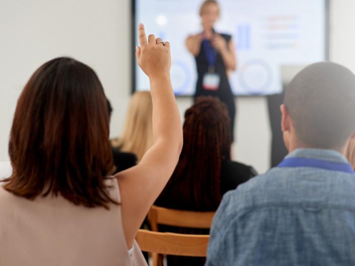 Woman raising her hand at a presentation.
