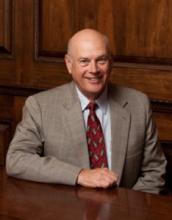 Headshot image of Tony Simmons, a man wearing a tan suit and red tie