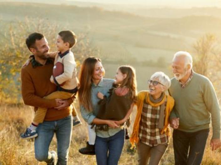 alt="Happy multi-generation family talking while taking a walk on a hill
