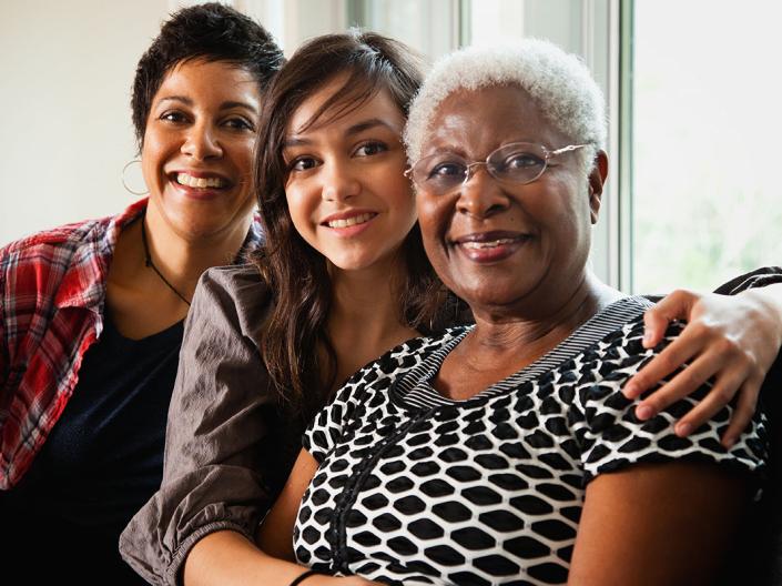 Three generations of women in business posing together and smiling