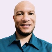Coby C. Williams smiles in a turquoise shirt.