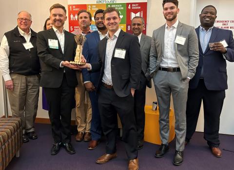 Impact Investing Competition second place team smiles with trophy and judges
