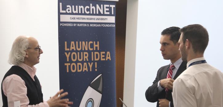 Photo of two students engaging with a representative for LaunchNET at a tabling event
