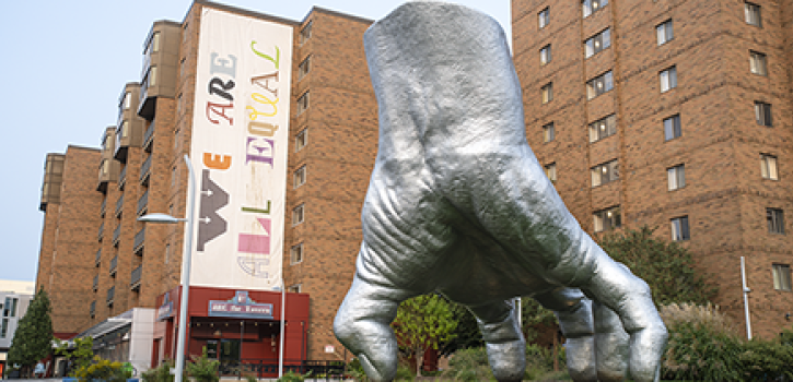 photo of the Judy's Hand sculpture in Uptown before a banner that reads "We are all equal" 