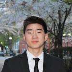 Darren Wang smiles in a suit outside.