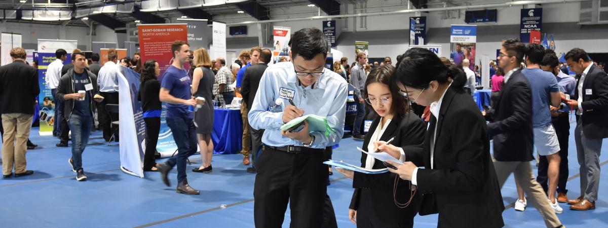 Three students compare notes at the career fair