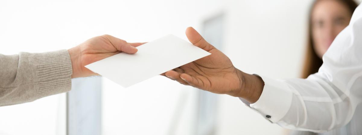 Close up shot of hands exchanging a white envelope