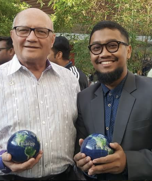 Chuck D. Fowler poses with student, both holding globe shaped awards