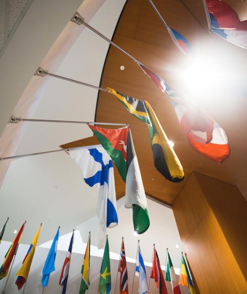photo of view from below looking up at flags from different countries hanging in the Peter B. Lewis Building
