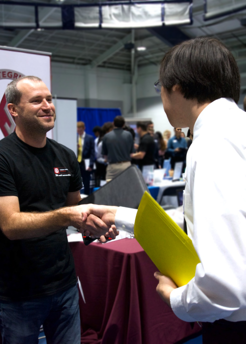 Student shakes hand of a company representative at the career fair