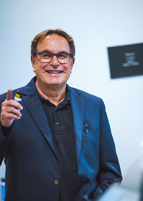 Portrait of David Cooperider smiling and holding a slide projector remote