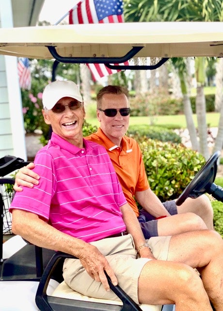Picture of Jack and David Dannemiller smiling in a golf cart