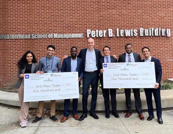 ETA pitch competition winners smile holding their checks with the dean.