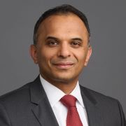 Headshot image of Swarup Katuri, a man wearing a black suit jacket and red tie