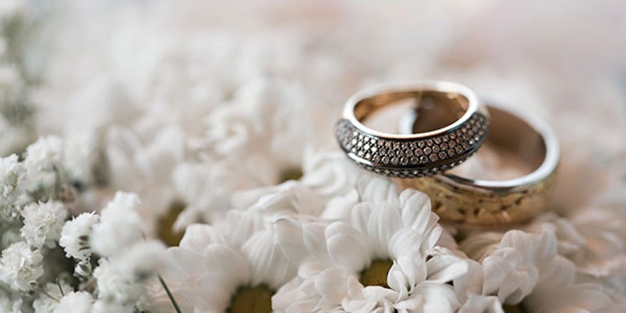 Two wedding rings laying on top of white flowers