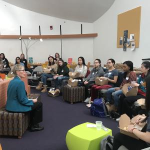 Female professor sitting with students in a casual lounge-style room