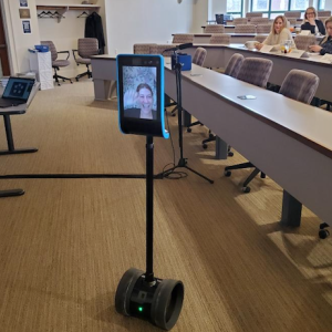Photo of Reesa Rotman's "telepresence robot" - an iPad with live video of her face sitting on top of a long pole attached to wheels