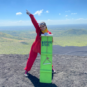 Photo of Elia Casanova  holding a sandboard atop a Volcano in Nicaragua