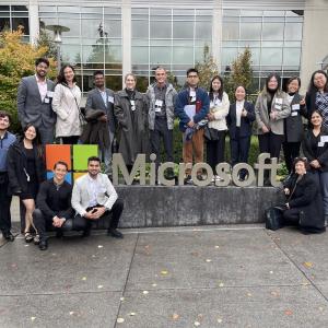 15 Graduate students posing next to the "Microsoft" sign outside the office in Seattle, WA