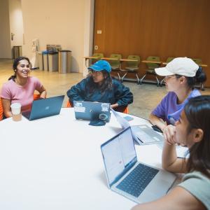 Undergraduate students sit around a table studying and talking.