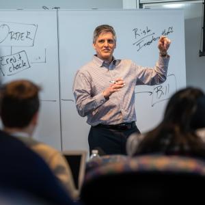 Tony Bucaro teaching at the white board in front of a class.