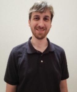 Noah Sitch smiles in a black polo against a white backgrounf
