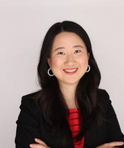 Yufan Dong smiles with her arms crossed in a black blazer.