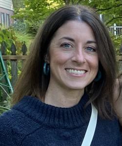 Alison Fitchpatrick smiles in a navy sweater outside.