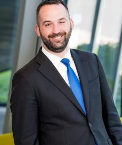 Headshot image of Kevin Lenahan, who is wearing a black suit jacket and blue tie