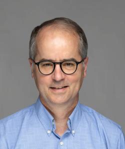 Headshot image of Mark Schweitzer, a man wearing a light blue shirt