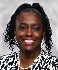 Headshot image of Sandra English, who is wearing a black and white blouse with a pearl necklace