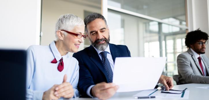 A stock photo of two business professionals talking while sitting at a table.