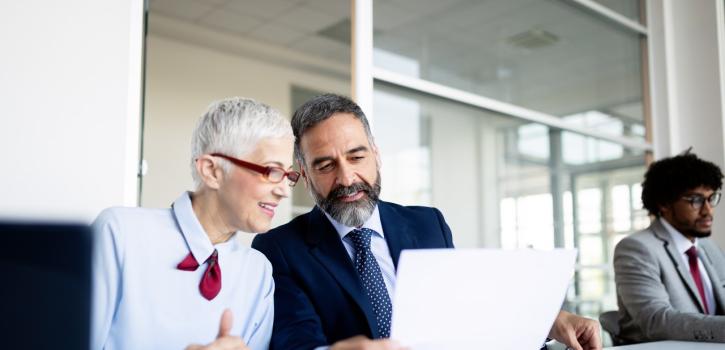 A stock photo of two business professionals talking while sitting at a table.