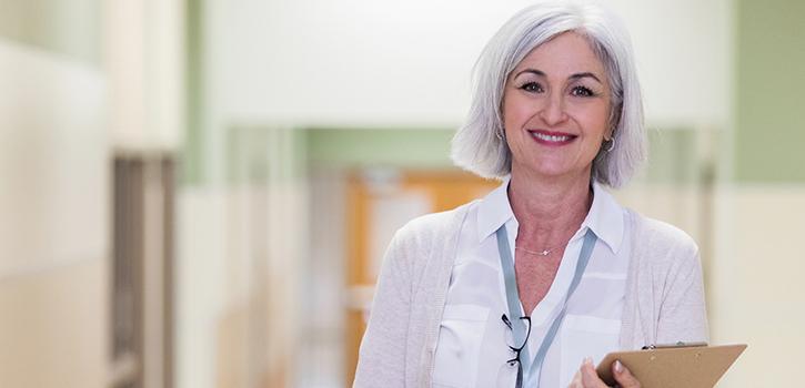 woman with clipboard smiling in a hallway