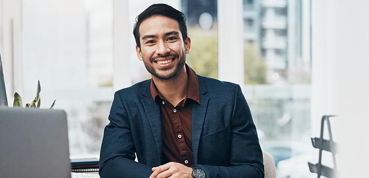 man smiling sitting in front of laptop