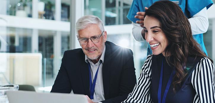 man and woman smiling while looking at laptop