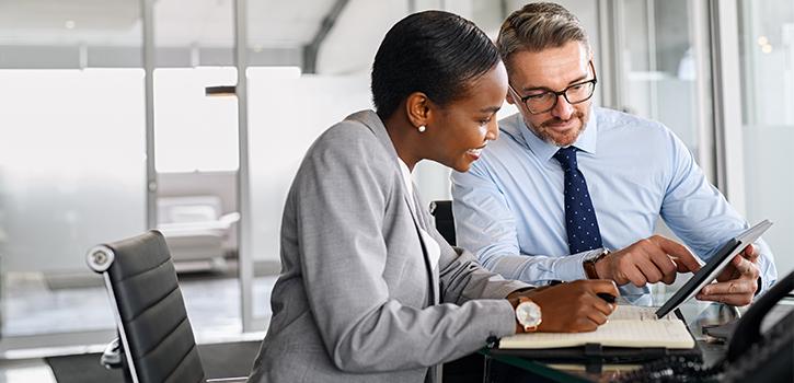 man and woman professionals looking at tablet