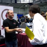 Student shakes hand of a company representative at the career fair